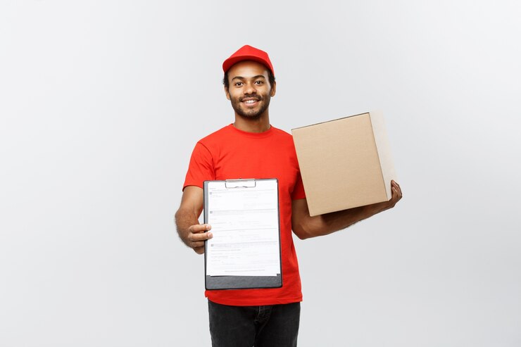 Free Photo delivery concept - portrait of handsome african american delivery man or courier showing a confirmation document form to sign. isolated on grey studio background. copy space.