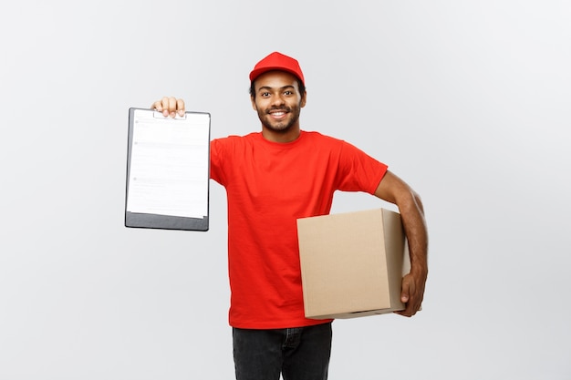 Delivery Concept - Portrait of Handsome African American delivery man or courier showing a confirmation document form to sign. Isolated on Grey studio Background. Copy Space.