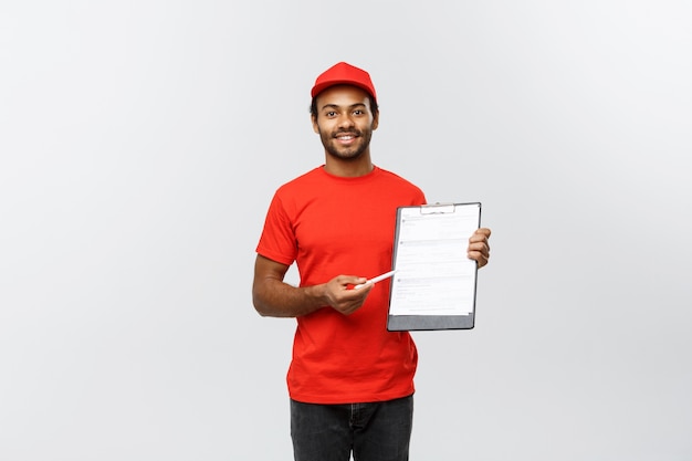 Delivery Concept - Portrait of Handsome African American delivery man or courier showing a confirmation document form to sign. Isolated on Grey studio Background. Copy Space.