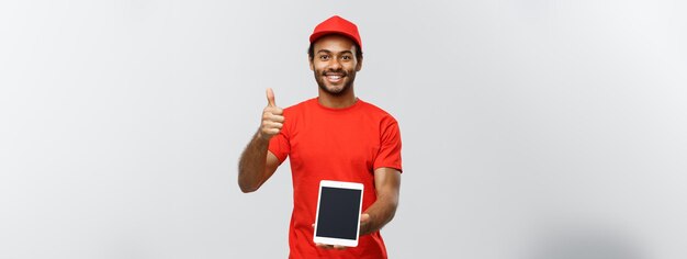 Delivery Concept Portrait of Handsome African American delivery man or courier showing tablet on you to check the order Isolated on Grey studio Background Copy Space