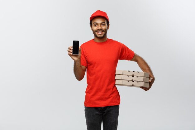 Delivery Concept - Portrait of Handsome African American delivery man or courier showing tablet on you to check the order. Isolated on Grey studio Background. Copy Space.