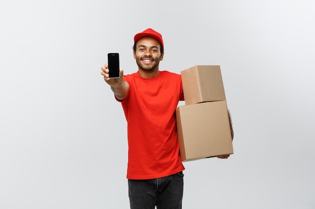 Delivery Concept - Portrait of Handsome African American delivery man or courier showing tablet on you to check the order. Isolated on Grey studio Background. Copy Space.