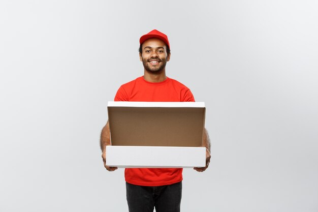 Concetto di consegna - ritratto di bello uomo di consegna pizza afroamericana. isolato su sfondo grigio dello studio. copia spazio.