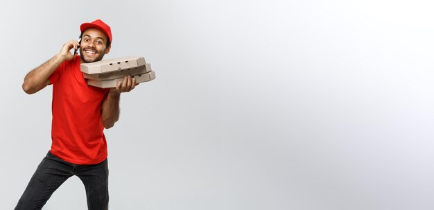 Delivery Concept Portrait of Handsome African American Pizza delivery man on phone with customer Isolated on Grey studio Background Copy Space