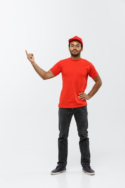 Delivery Concept - Portrait of Happy African American delivery man pointing hand to present something. Isolated on Grey studio Background. Copy Space.