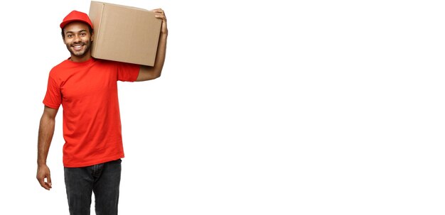 配達の概念白いスタジオで隔離のボックスパッケージを保持している赤い布で幸せなアフリカ系アメリカ人配達人の肖像背景コピースペース