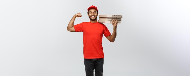 회색 스튜디오 배경 복사 공간에 격리된 피자 상자 패키지로 근육을 보여주는 강력한 아프리카계 미국인 배달부의 배달 개념 초상화