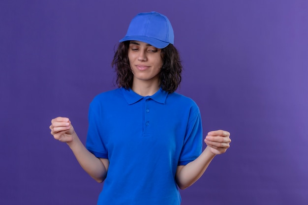 青い制服を着た配達の女の子と手で自信を持って身振りで示すキャップ、孤立した紫の上に立って身体言語の概念
