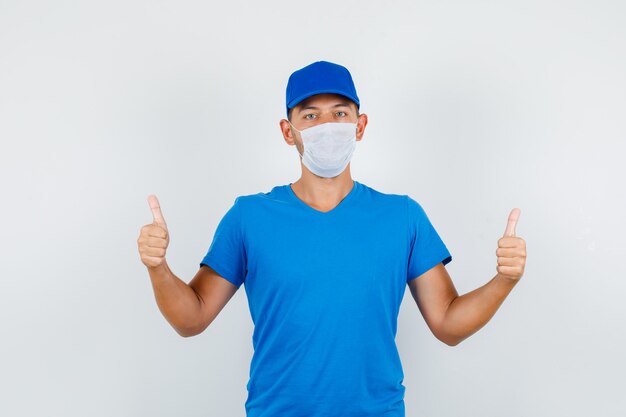 Delivery man in blue t-shirt, cap, mask showing thumbs up