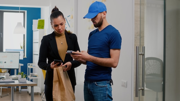 Delivery man bringing takeaway food meal order to businesswoman in startup company office