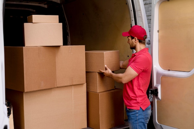 Free photo delivery man at car taking packages