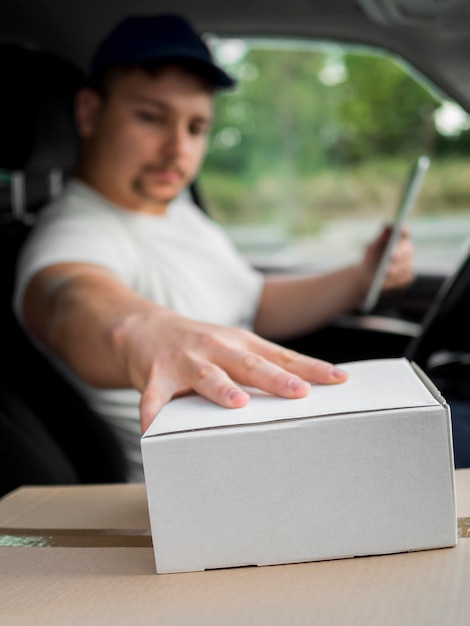 Delivery man in car touching box
