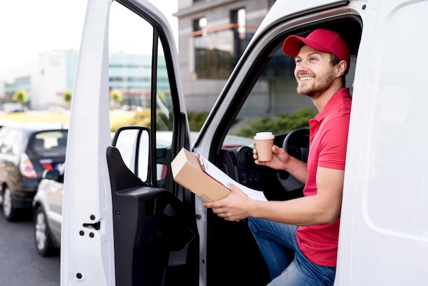 Delivery man in car with coffee