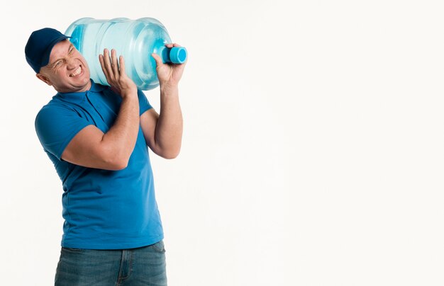 Delivery man carrying heavy water bottle on shoulder