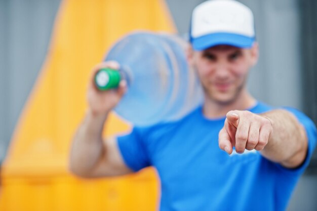 Delivery man carrying water bottle on shoulder and show finger to camera