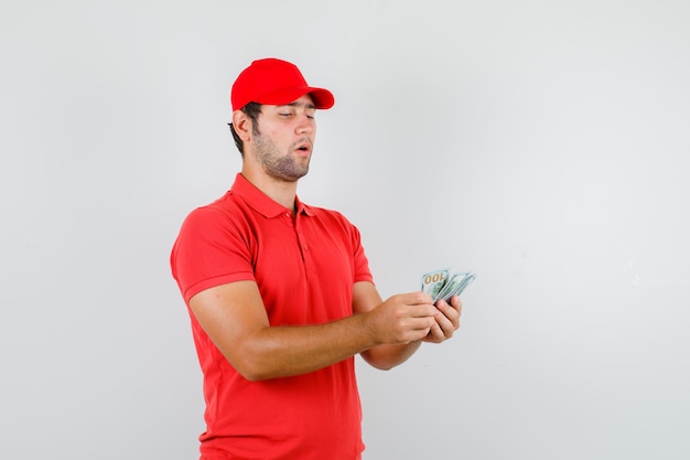 Доставщик, считающий долларовые банкноты в красной футболке