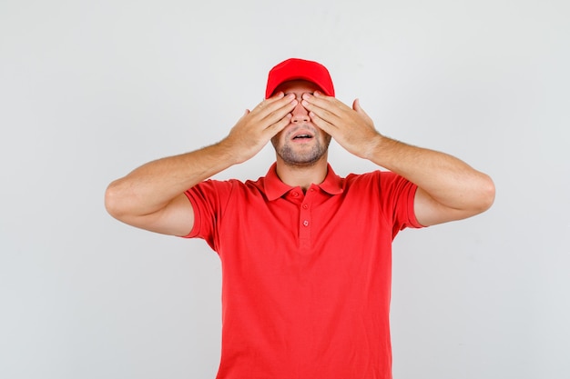 Delivery man covering eyes with hands in red t-shirt