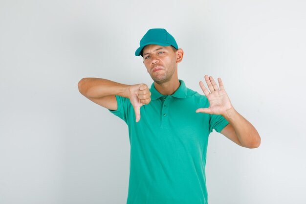 Delivery man gesturing no and showing thumb down in green t-shirt and cap
