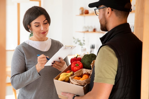 Uomo di consegna che dà l'ordine di generi alimentari al cliente