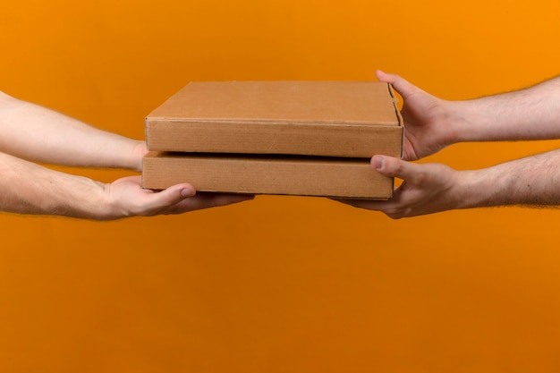 Free photo delivery man giving pizza boxes to customer on isolated orange side view