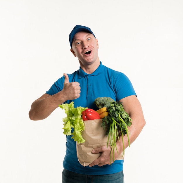 Delivery man giving thumbs up and holding grocery bag