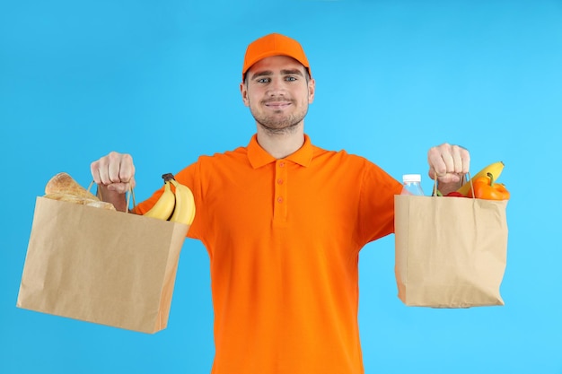 Delivery man hold bags with food on blue background