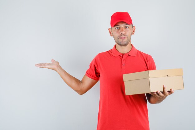 Delivery man holding cardboard box in red uniform