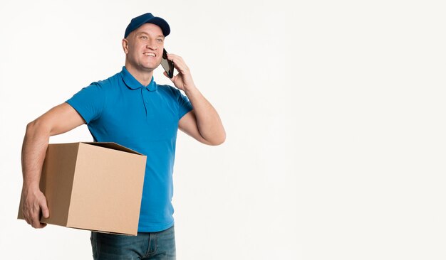 Delivery man holding cardboard box and smartphone