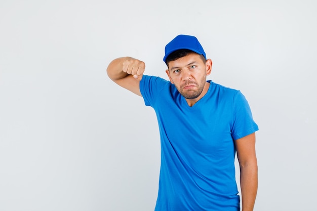 Delivery man holding fist for threatening in blue t-shirt