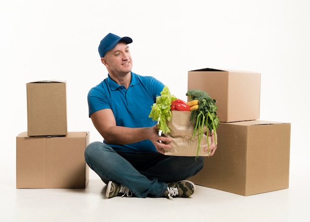 Free photo delivery man holding grocery bag and smiling