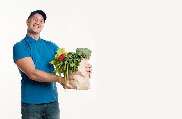 Delivery man holding grocery bag with copy space