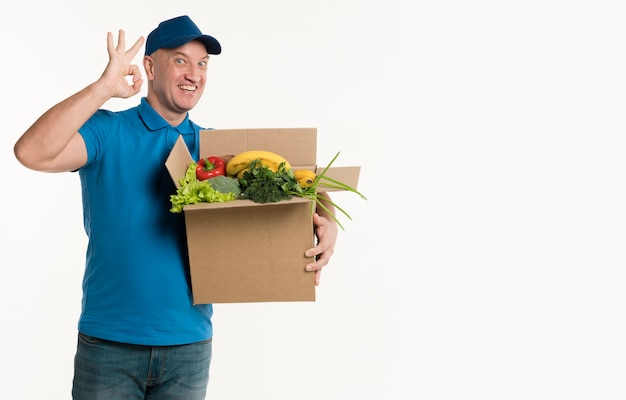 Delivery man holding grocery box and showing okay sign