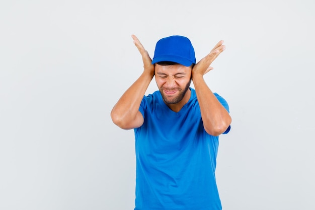 Delivery man holding hands on ears in blue t-shirt