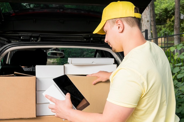 Free photo delivery man holding tablet and box