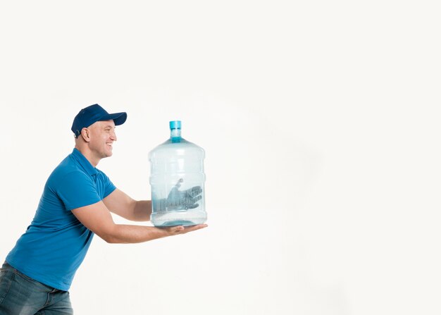 Доставка человек, держа бутылку воды и позирует