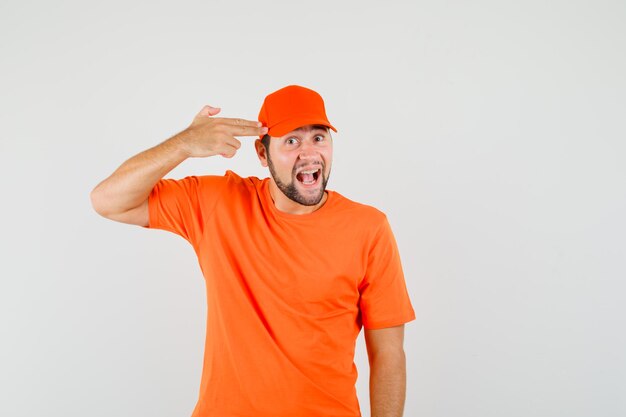 Delivery man making suicide gesture in orange t-shirt, cap and looking amused. front view.