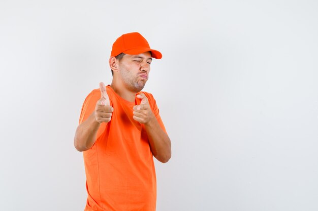 Delivery man in orange t-shirt and cap imitating gun gesture