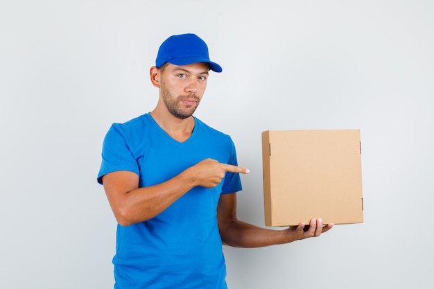 Delivery man pointing at cardboard box in blue t-shirt