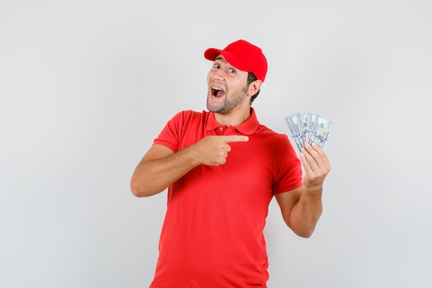 Доставщик, указывая на долларовые банкноты в красной футболке