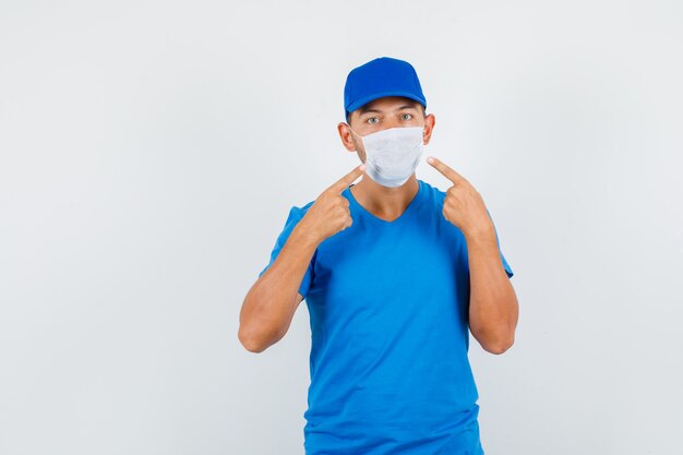 Delivery man pointing at his mask in blue t-shirt