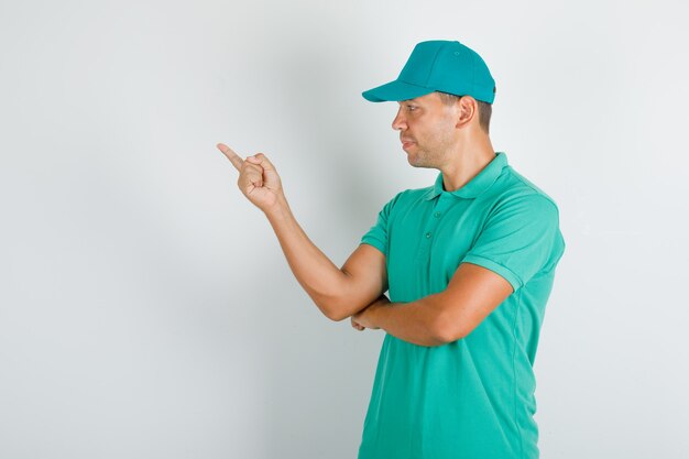 Delivery man pointing to the side in green t-shirt with cap