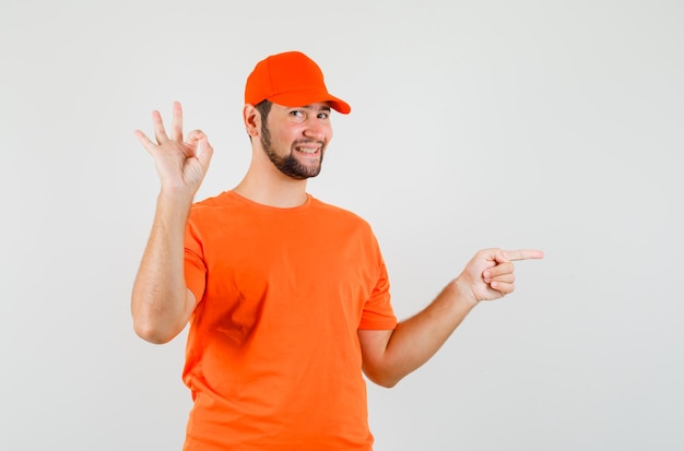 옆을 가리키는 배달원은 주황색 티셔츠, 모자를 쓰고 쾌활한 표정을 짓고 있다. 전면보기.