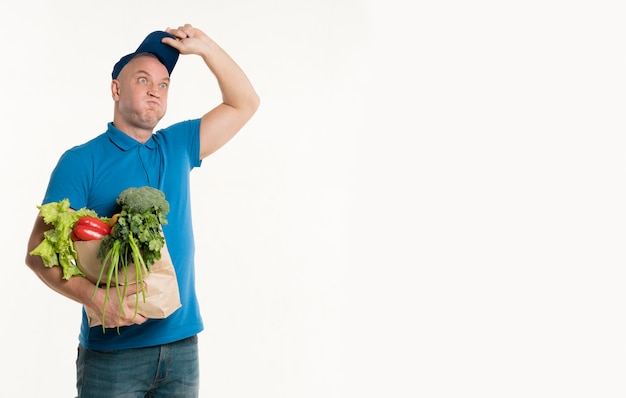 Delivery man posing silly while holding grocery bag