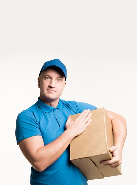 Delivery man posing while touching cardboard box