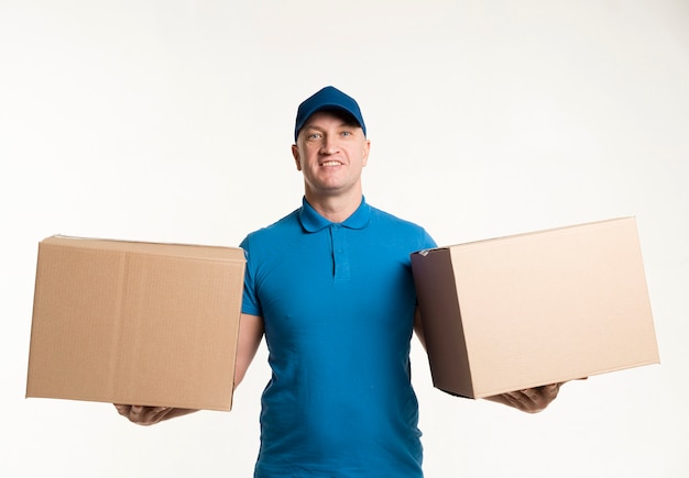 Free photo delivery man posing with cardboard boxes in each hand