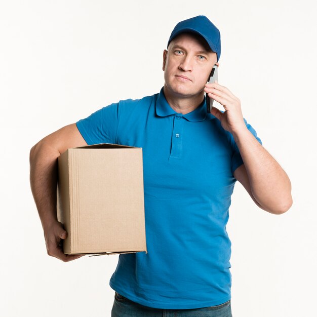 Delivery man posing with smartphone and cardboard box