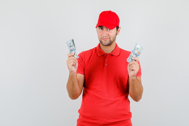 赤いTシャツ、ドル紙幣を保持し、前向きに見えるキャップの配達人