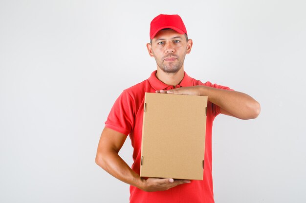 Delivery man in red uniform holding cardboard box