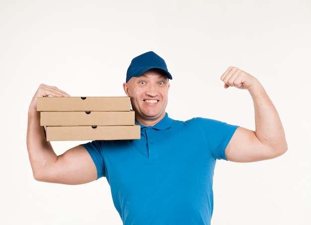 Uomo di consegna che mostra bicipite mentre trasportava scatole per pizza