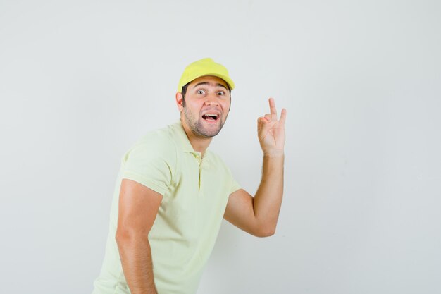 Delivery man showing ok sign in yellow uniform and looking happy. front view.